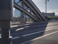 a person rides down the street in front of a large building with a bridge in the background