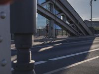 a person rides down the street in front of a large building with a bridge in the background