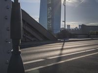 a person rides down the street in front of a large building with a bridge in the background