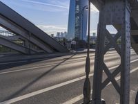 a person rides down the street in front of a large building with a bridge in the background