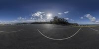 the sun is shining above the clouds in a sunny day from a circular lens at the side of the asphalt