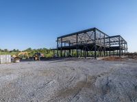 a picture of a building being built on a field near a forest in the background