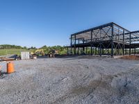 a picture of a building being built on a field near a forest in the background