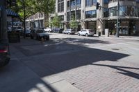 a city sidewalk with parked cars and tall buildings behind it's windows and shadows