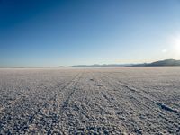 a snow covered desert with mountains in the background is shown here and there are tracks on it