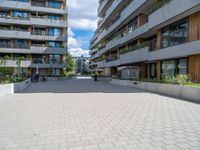 the empty sidewalk in front of apartment buildings on a sunny day, as well as two bicycles parked