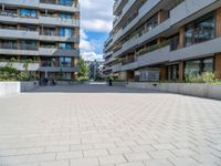 the empty sidewalk in front of apartment buildings on a sunny day, as well as two bicycles parked