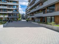 the empty sidewalk in front of apartment buildings on a sunny day, as well as two bicycles parked