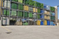 a bunch of pallets with different colors are in a storage area near some containers