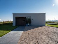 the driveway leading into a modern, minimal residence in tuscany with its large concrete building and concrete flooring