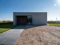 the driveway leading into a modern, minimal residence in tuscany with its large concrete building and concrete flooring