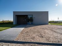 the driveway leading into a modern, minimal residence in tuscany with its large concrete building and concrete flooring