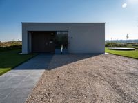 the driveway leading into a modern, minimal residence in tuscany with its large concrete building and concrete flooring