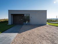 the driveway leading into a modern, minimal residence in tuscany with its large concrete building and concrete flooring