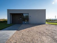 the driveway leading into a modern, minimal residence in tuscany with its large concrete building and concrete flooring