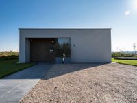 the driveway leading into a modern, minimal residence in tuscany with its large concrete building and concrete flooring