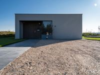 the driveway leading into a modern, minimal residence in tuscany with its large concrete building and concrete flooring