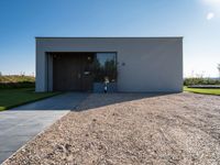 the driveway leading into a modern, minimal residence in tuscany with its large concrete building and concrete flooring