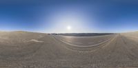 an empty parking lot surrounded by large hills and empty roads in a sunny day with a clear sky above