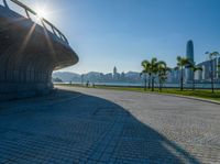 a walkway with an arch and palm trees along it on a sunny day near the water