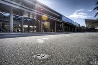 a very empty street at an airport terminal by some buildings and trees on a sunny day