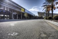 a very empty street at an airport terminal by some buildings and trees on a sunny day