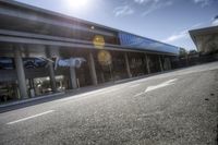 a very empty street at an airport terminal by some buildings and trees on a sunny day