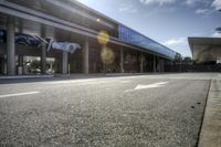 a very empty street at an airport terminal by some buildings and trees on a sunny day