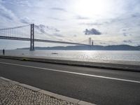 a road leading to an underpass with the forth bridge in the background and a body of water at the far end