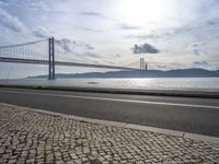 a road leading to an underpass with the forth bridge in the background and a body of water at the far end