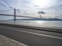 a road leading to an underpass with the forth bridge in the background and a body of water at the far end