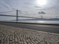 a road leading to an underpass with the forth bridge in the background and a body of water at the far end