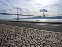 a road leading to an underpass with the forth bridge in the background and a body of water at the far end