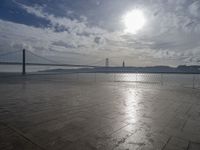 a bridge that is over the water and sky in the background is lit by the sun