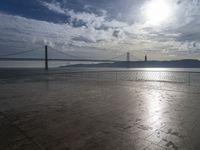 a bridge that is over the water and sky in the background is lit by the sun