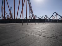 a park has many roller coasters set up for rides with multiple lines of orange painted and orange colored railings