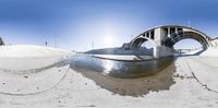 the fish - eye view of a boat out on the beach under a bridge on a sunny day