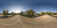 a panoramic lens image of a dirt road and a car on a sunny day