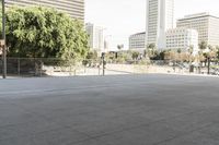 a woman is skateboarding in an outdoor courtyard area near buildings and trees, there are also people around