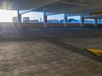 an empty garage with parking spaces and sun flares on the ground with the sun shining brightly