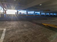 an empty garage with parking spaces and sun flares on the ground with the sun shining brightly