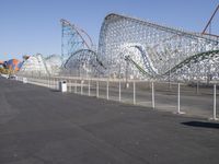 a very tall roller coaster in an empty park surrounded by roller coasters and cranes