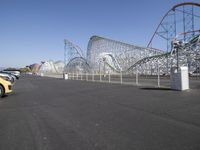 a very tall roller coaster in an empty park surrounded by roller coasters and cranes