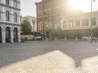 the sun shines over the town square with buildings in the background and parked cars parked