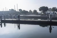 a woman is on the dock by the water while another watches her surroundings and people are walking