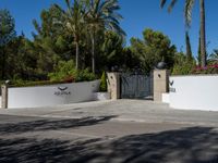 the gate to a building at the entrance to an upscale estate with palm trees in the background