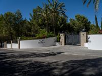 the gate to a building at the entrance to an upscale estate with palm trees in the background