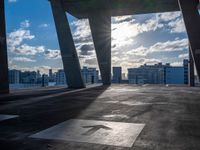 a street view of several huge structures and sky in the background with sun peaking through