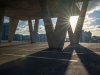 the sun shines brightly through a set of columns on the roof of an urban building