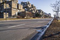 an empty road is near a street with some buildings on it in the background on a sunny day